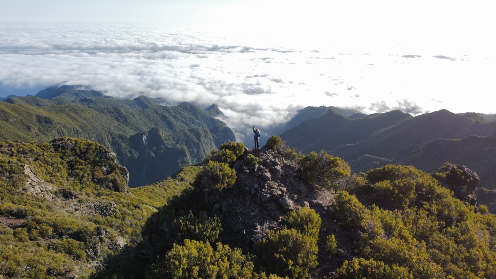 Svenja standing on a mountain peak above a sea of clouds in Madeira