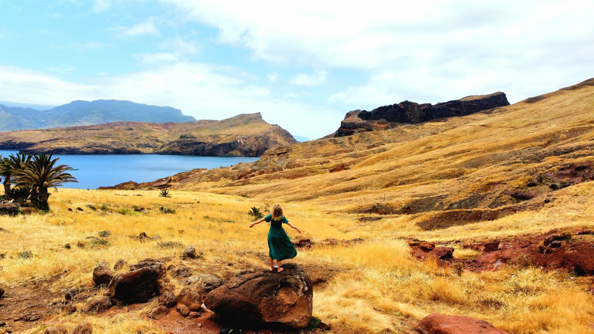 Svenja standing on a rock above the sea in Madeira, arms open